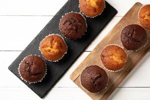 Delicious variety of fresh muffins displayed on wooden and slate serving boards photo