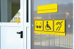 Accessibility signs displayed on the entrance of a public building for individuals with special needs photo