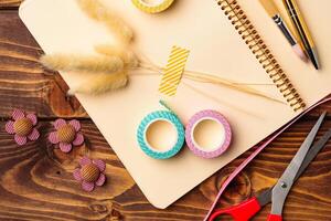 Crafting materials arranged on a wooden table along with a notebook and scissors for creative projects photo