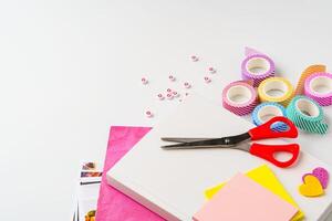 Crafting materials arranged for a creative project featuring scissors, colored paper, and decorative tape on a workspace photo