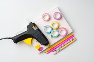Craft supplies arranged on a table with a glue gun, washi tape, and colored pencils ready for a creative project photo