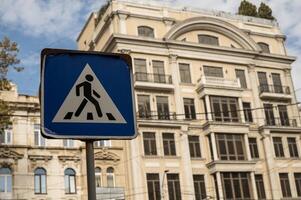 A street sign in front of a building. High quality photo. pedestrian crossing sign in the city with a building in the background. road sign in the city and a large residential building behind it photo