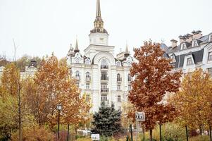 bright autumn in a residential area. bright yellow and red trees in the foreground. residential building in the distance. yellow trees are maple and birch and a pine tree grows. photo