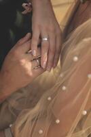 wedding rings at a wedding and hands close-up. bride's hand and groom's hand. photo has a vertical orientation. gold rings on elegant hands. bride's beige dress with pearls is visible