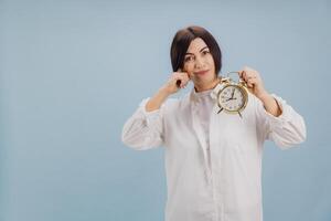 Mature woman covering ears ignoring alarm clock ringing in studio photo