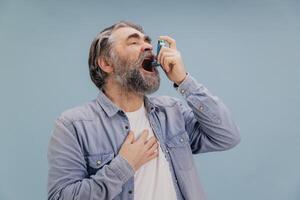 Senior man using asthma inhaler during breathing problems photo