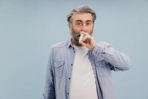 Senior man using nasal spray for treating rhinitis and preventing flu photo