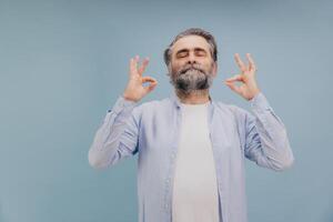 Senior man practicing yoga and meditation with closed eyes and calm expression photo