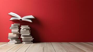 Open book above stacked books on wooden floor with red wall photo