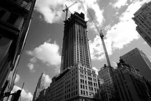 Construction activity on a high-rise building in an urban area with cranes and a cloudy sky photo