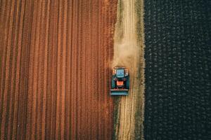 Tractor working in freshly tilled soil between fields at sunset time showcasing agricultural practices photo