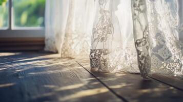 Sheer lace curtains gently sway in sunlight illuminating a wooden floor in a tranquil indoor space photo