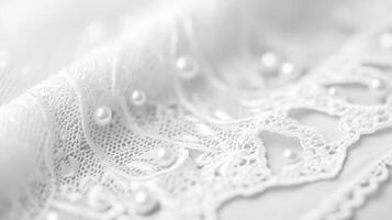 Delicate white lace with pearls placed gracefully on soft fabric during a crafting session in natural light photo