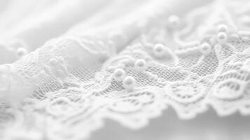Delicate white lace fabric with small pearls seen up close in soft lighting during daytime photo