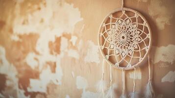 Decorative dream catcher hangs on a textured wall in a softly lit room, showcasing intricate lace design and natural materials photo