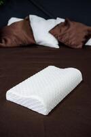 A white pillow on a bed with brown pillows photo