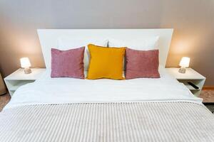 A bed with a white headboard and a bedside table photo