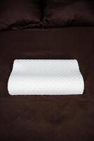 A white pillow on a bed with brown sheets photo