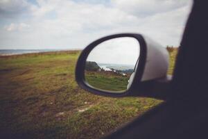 A car side view mirror with a view of a field photo