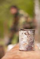 An old tin can on a wooden table with a man in the background photo