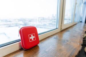 A red first aid kit sitting on a window sill photo