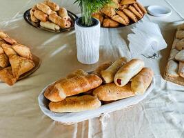 A table with a bunch of breads and a plant photo