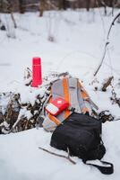 A backpack and a water bottle are sitting in the snow photo