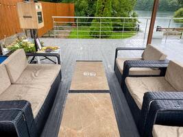 A deck with furniture and a table in front of a lake photo