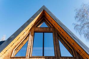 A wooden house with a triangular roof and windows photo