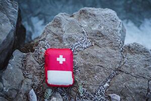 A red first aid kit laying on the rocks photo