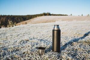 A thermos is sitting on the ground in the middle of a field photo