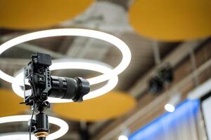 A camera on a tripod in front of a circular light photo