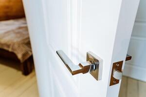A white door with a handle and a bed photo