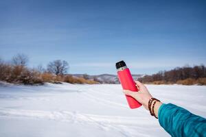A person holding a red lighter in the snow photo