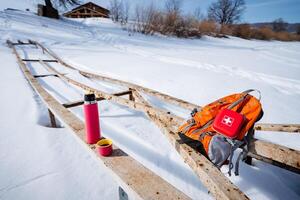 A wooden bench with a backpack and a water bottle photo