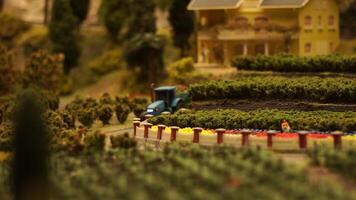 A tractor model with a trailer moves through the countryside. Footage. Conceptual representation of rural life in toy models. video