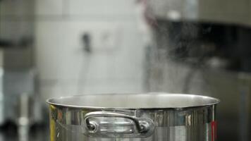 Vapour clouds rising from boiling water in pan on stove. Media. Steam and white smoke rising on professional kitchen background. Steam from pan while cooking. Cooking process in slow motion. video