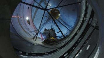 An experienced worker is safely and effectively carrying out tasks inside a large tank. Media video