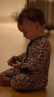 A Candid Child is Happily Playing with a Toy While Dressed in Cozy and Colorful Pajamas video