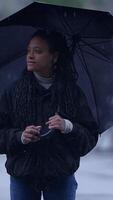 A woman is holding a colorful umbrella while thoughtfully standing in the rain on a cloudy, wet day video