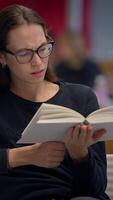 un enfocado lector aparece profundamente comprometido en un cautivador libro conjunto dentro un moderno ambiente video
