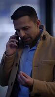 A man is deeply engaged in a conversation on his mobile phone while in an urban setting video