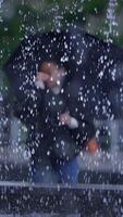 A solitary man holding an umbrella stands in a rainy urban environment, creating a moody atmosphere video