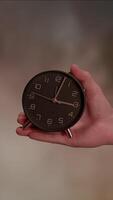 A vintage clock held in hand against a blurred background, creating an intriguing focal point video