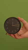 A black clock against a vibrant green background, showcasing its unique design and elegance video