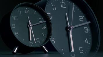 A collection of stylish black alarm clocks showcased against a dark background setting video