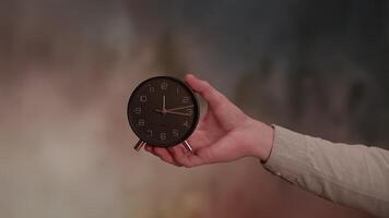 A Hand Holding a Classic Black Alarm Clock Set Against an Artistic and Colorful Background video