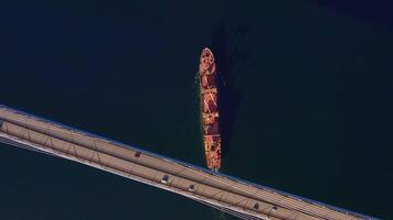 A top down view of a vessel in motion passing under a bridge video