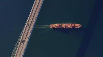 A top down view of a vessel in motion passing under a bridge video