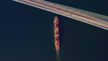 A top down view of a vessel in motion passing under a bridge video